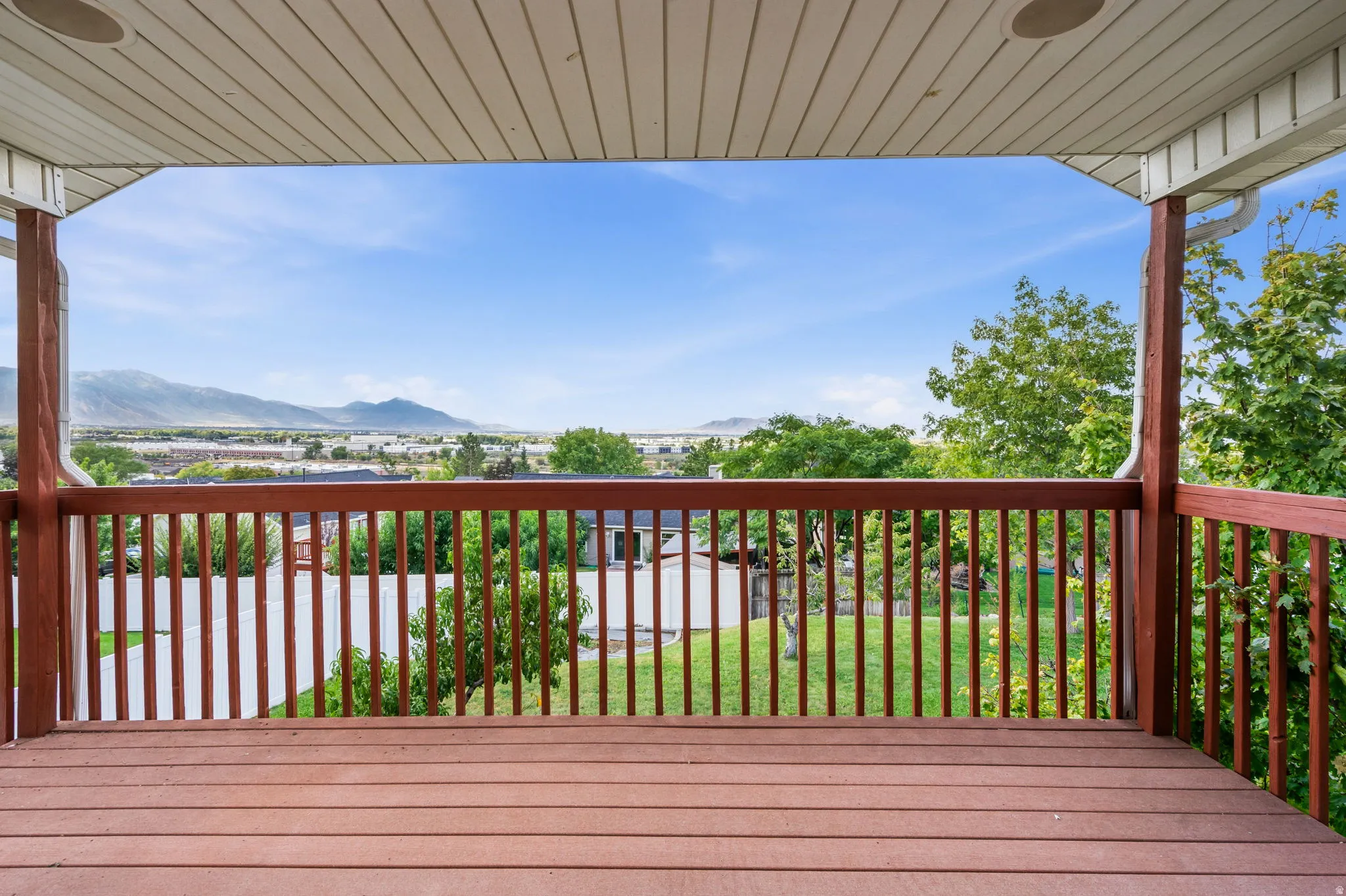 Expansive covered deck featuring wood-finish flooring, wood railings, and mountain scenery