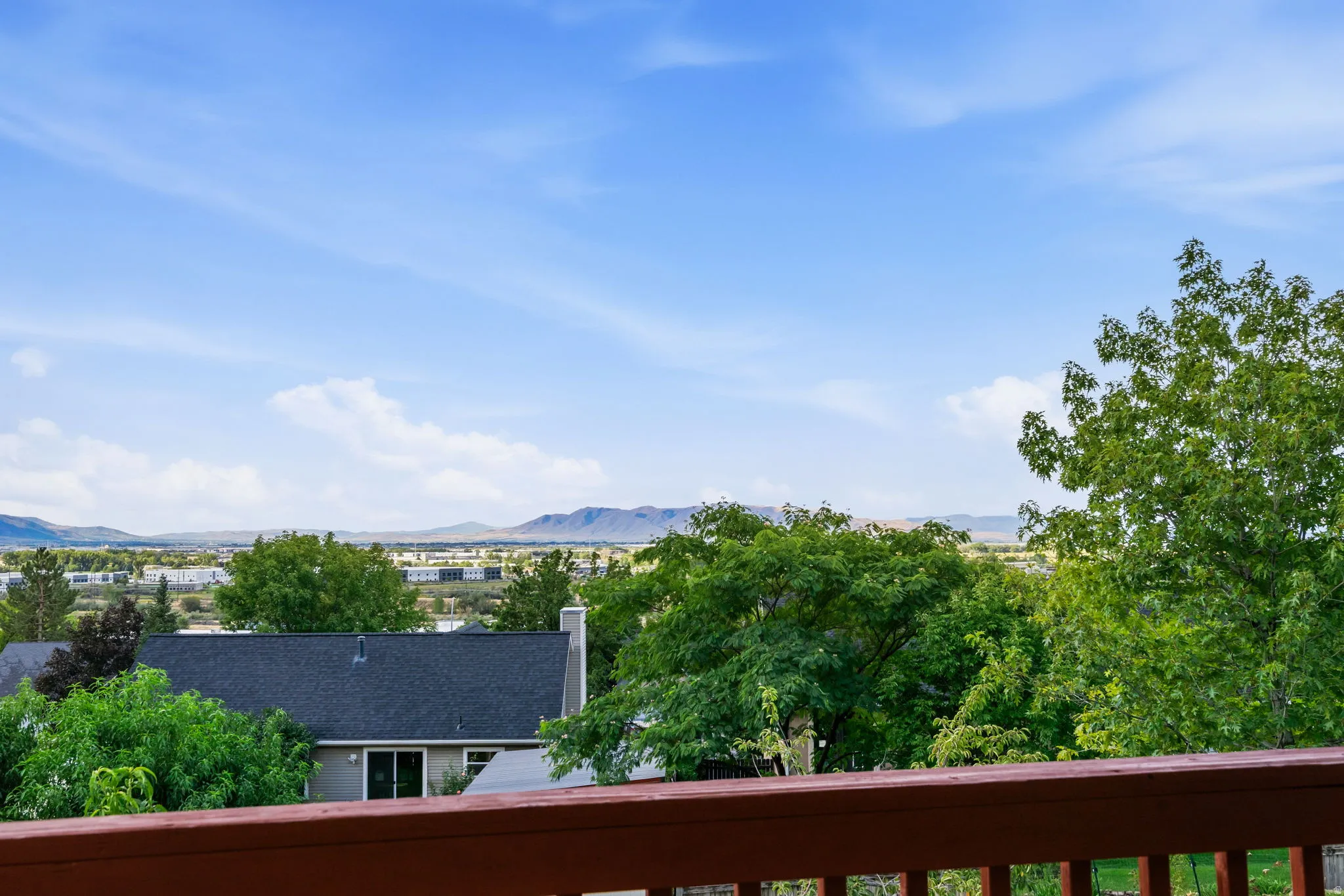 Wood-tone railing with a distant mountain backdrop and lush green trees