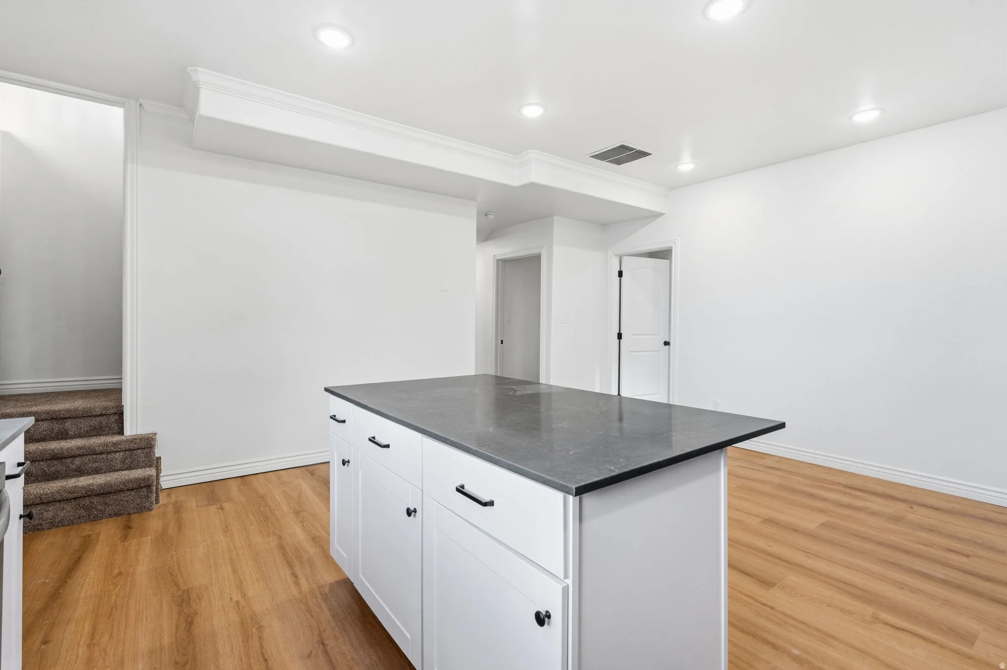 Kitchen island with dark countertop, white cabinetry, and matte black hardware