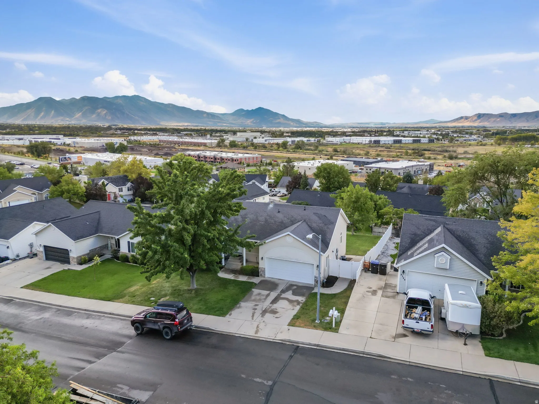 Residential property featuring a paved driveway, attached garage, and mature landscaping