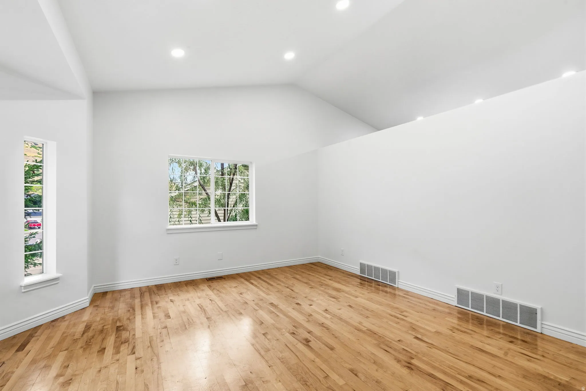 Vaulted ceilings, recessed lighting, wood-finish flooring, and white trim