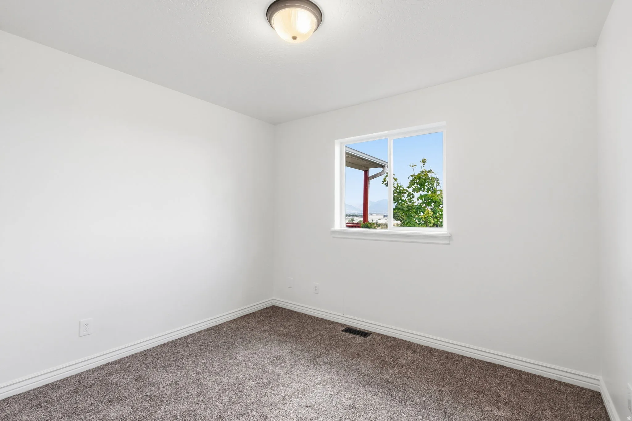 Recessed ceiling light fixture, white walls, carpeted flooring, and a single window