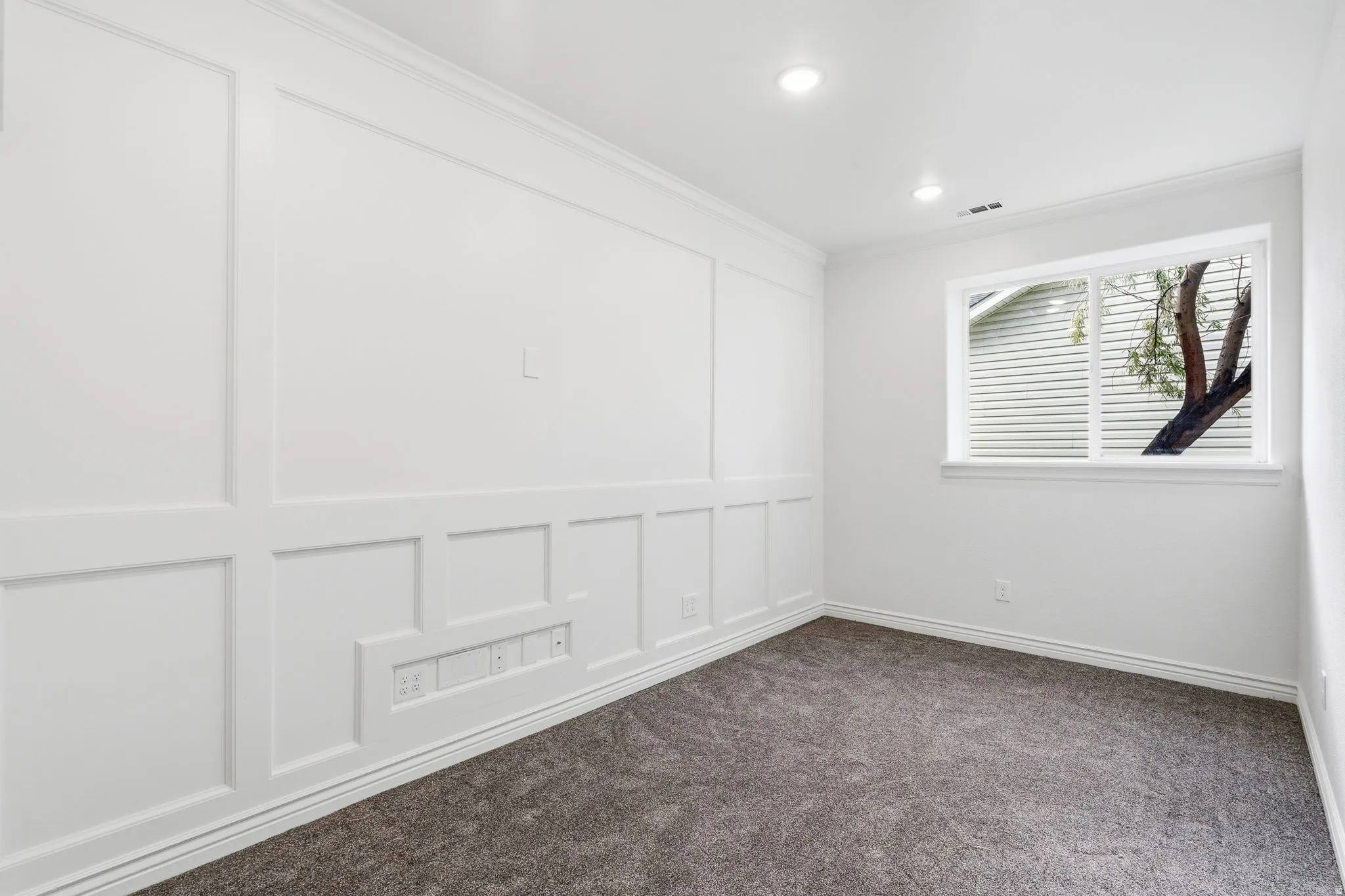 Accent wall with wainscoting detail, recessed lighting, white trim, and gray carpeting