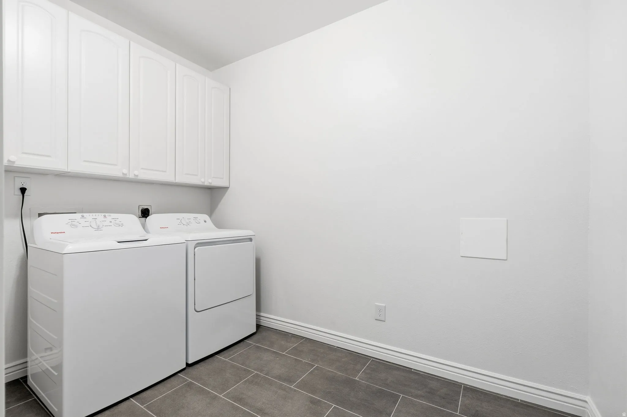 White upper cabinetry with recessed panel doors, tile flooring, and neutral wall tones