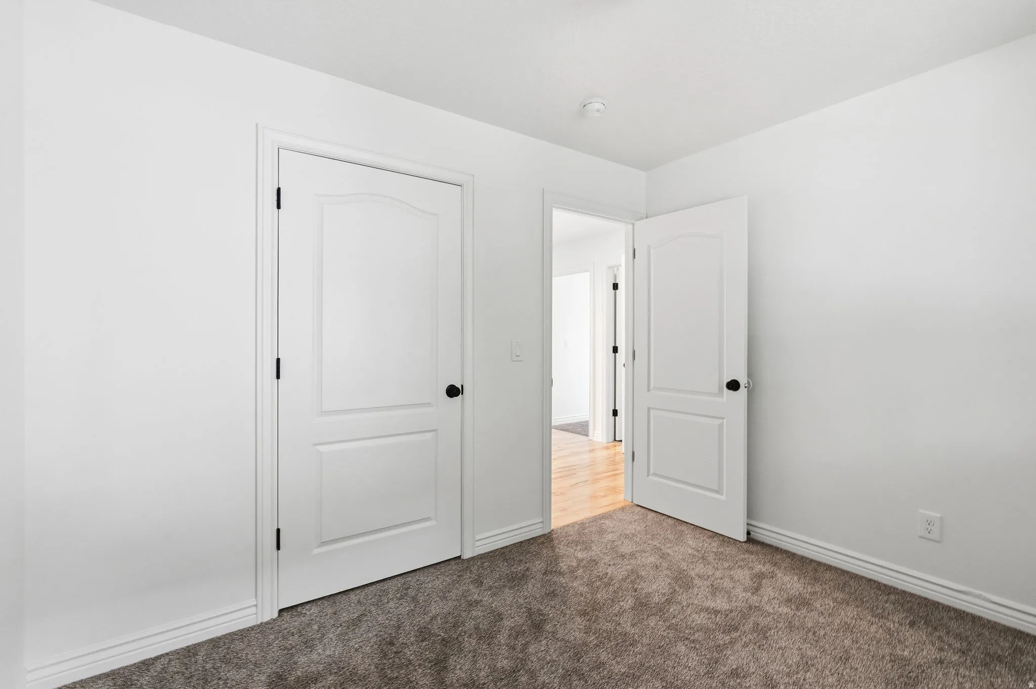White interior doors with black hardware, white trim, and carpeting