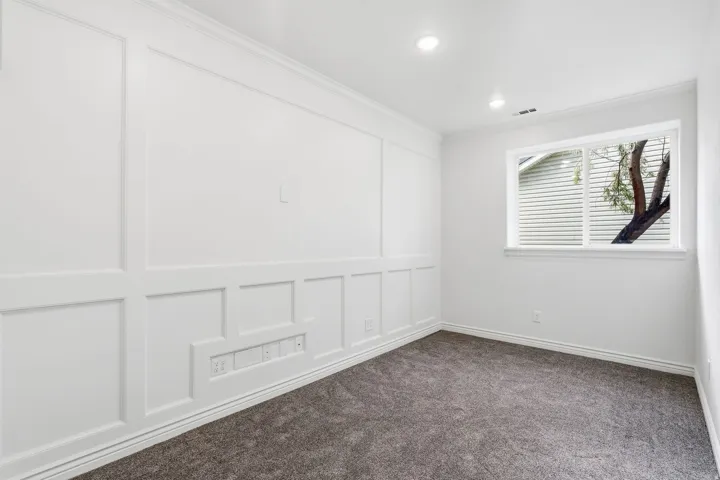Accent wall with wainscoting detail, recessed lighting, white trim, and gray carpeting