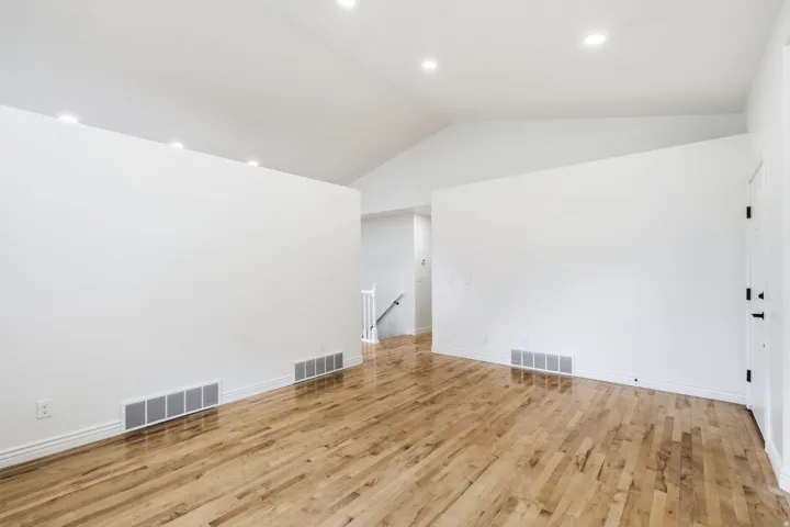Vaulted ceiling with recessed lighting, light wood-finish flooring, and white interior walls