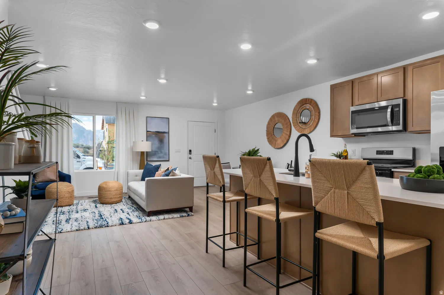 Open-concept living space featuring wood-finish flooring, recessed lighting, and a kitchen island with seating