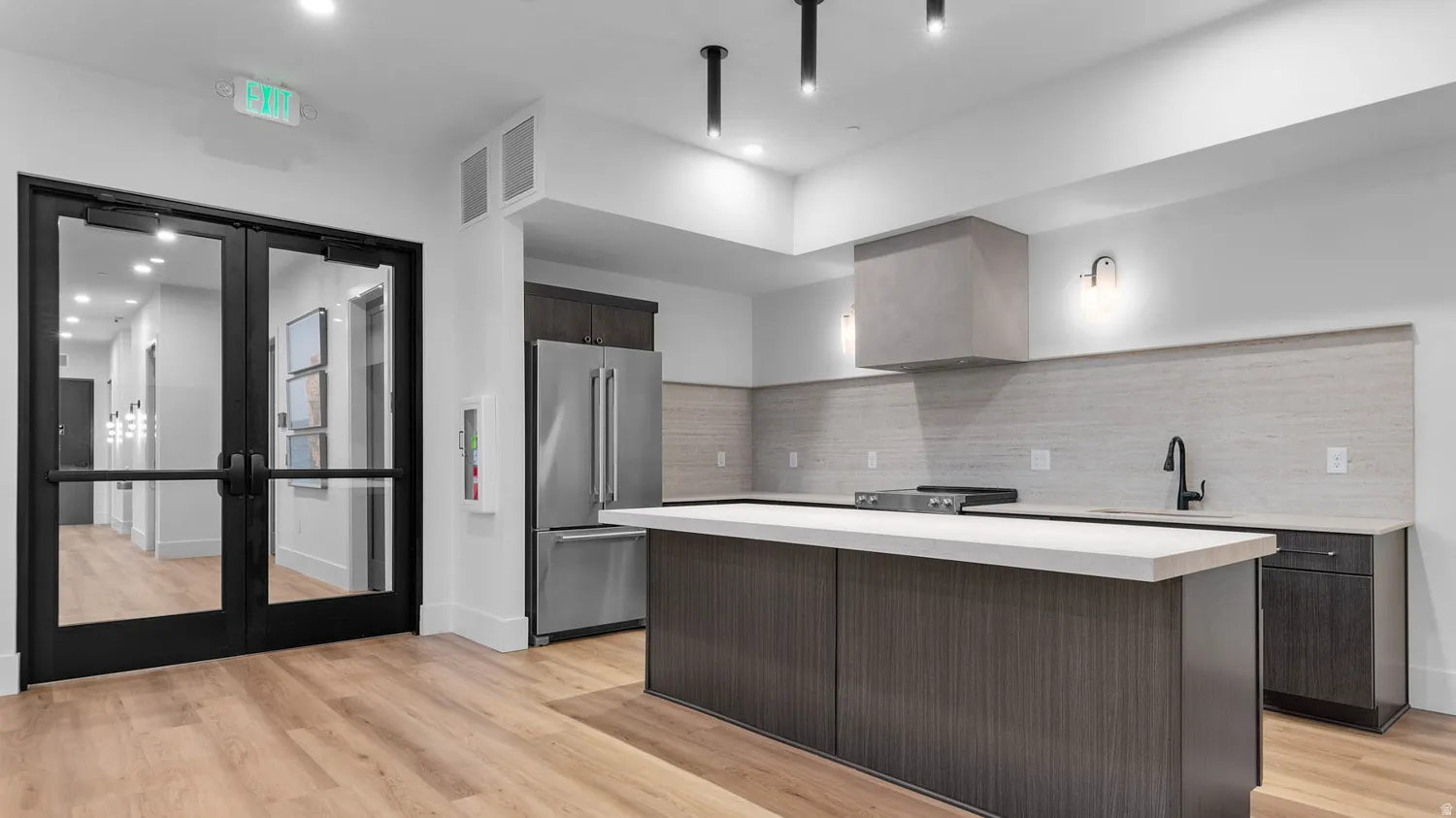 Modern kitchen with a substantial island, stainless steel refrigerator, and integrated range hood