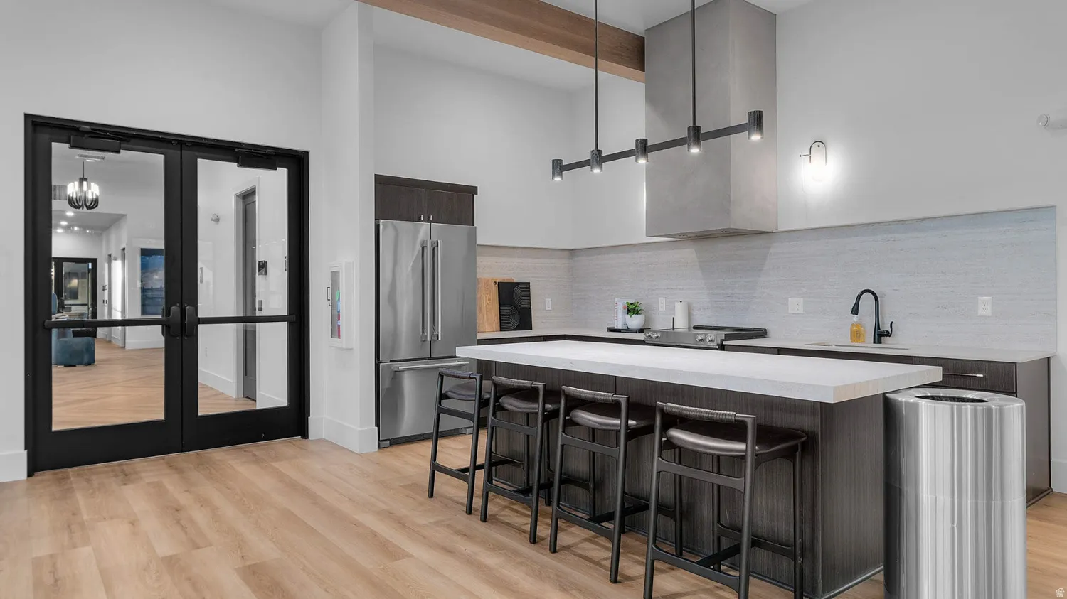 Spacious open-concept kitchen featuring a large island with seating, stainless steel appliances, a linear pendant light fixture, and wood-finish flooring