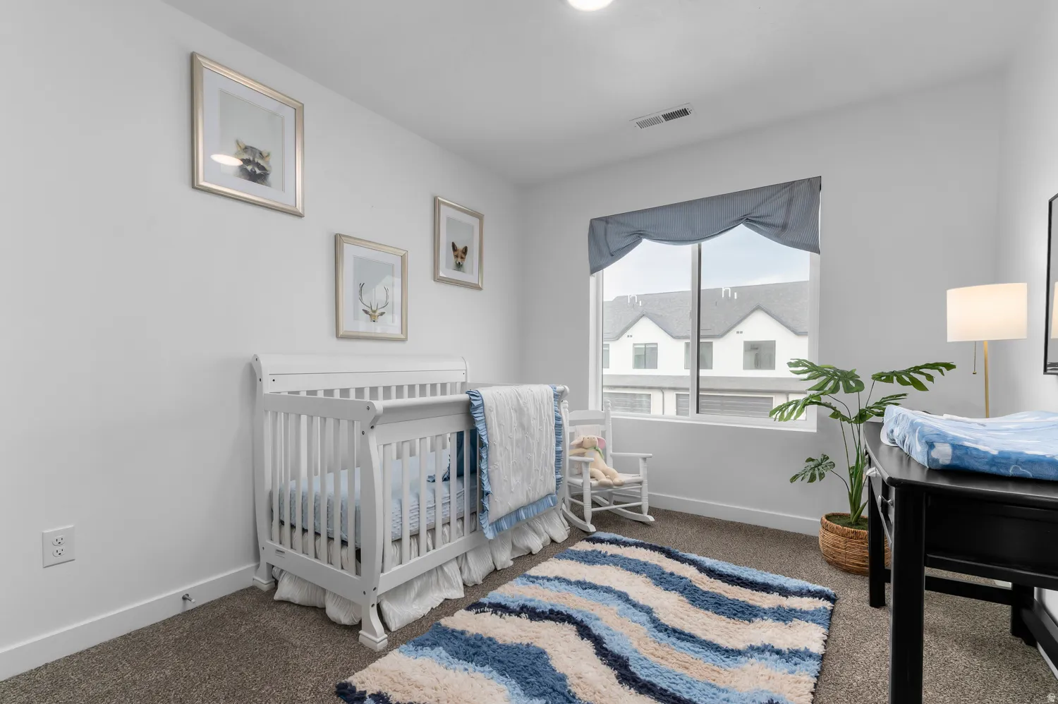 Carpeted room featuring a large window, white walls, and a built-in overhead light