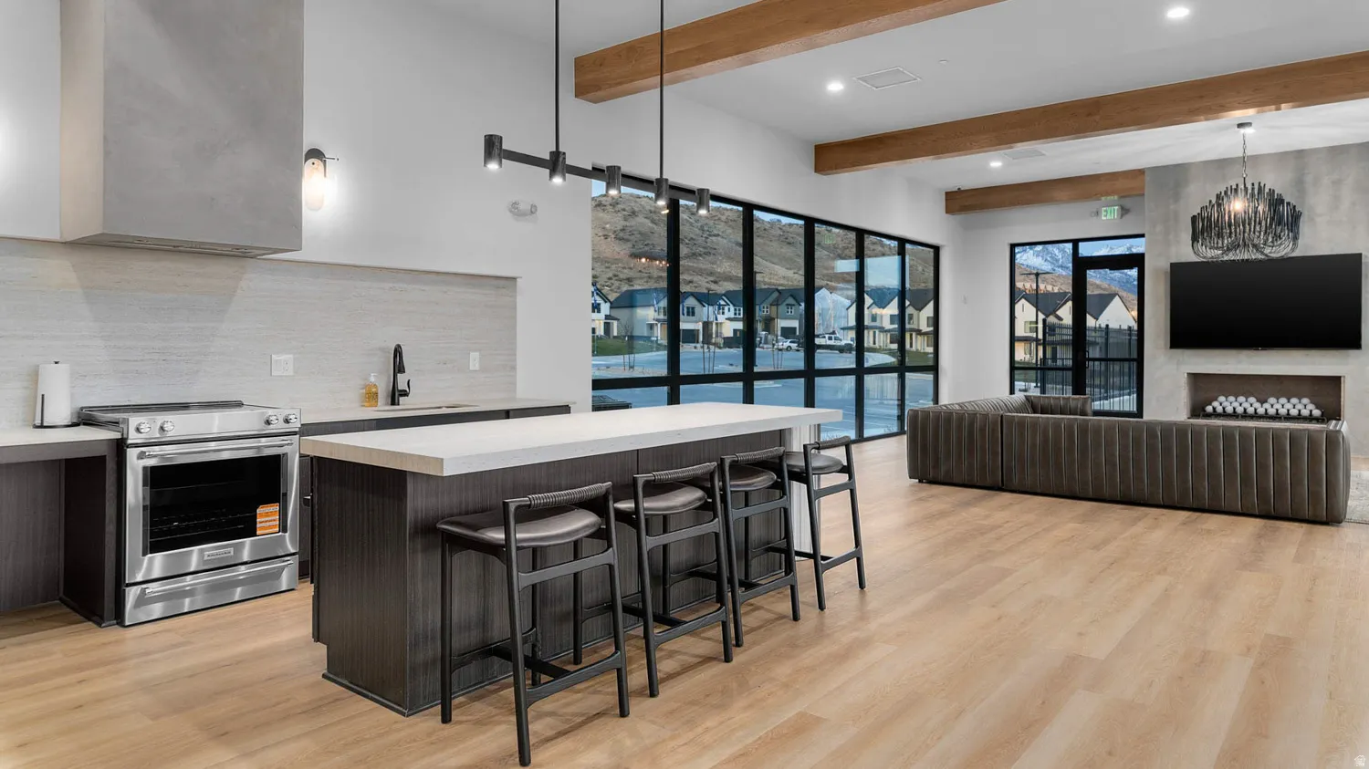 Open-concept living space with wood-finish flooring, a contemporary fireplace, and a kitchen island featuring a light-toned countertop