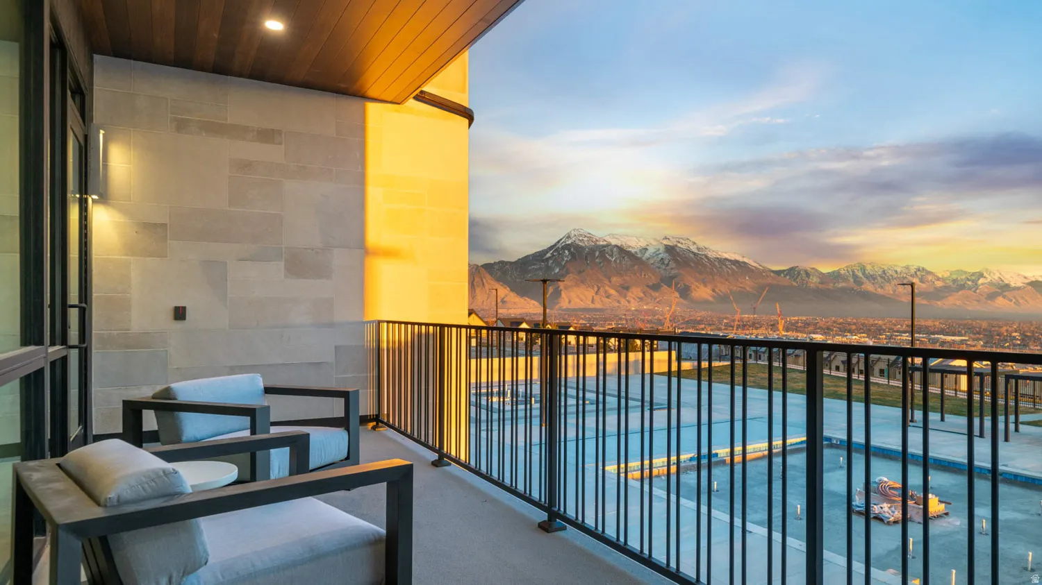 Outdoor balcony with a wood-finish ceiling, mounted wall sconces, and metal railings