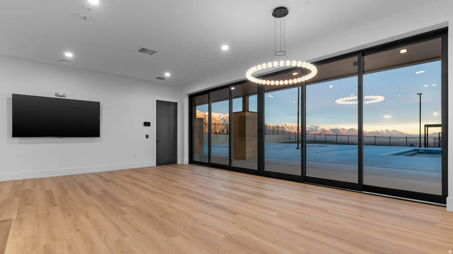 Wood-finish flooring, recessed lighting, and a contemporary chandelier