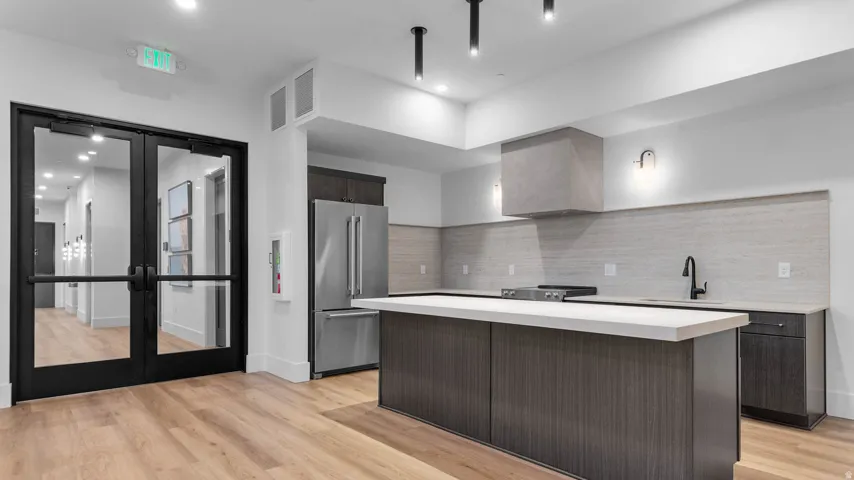 Modern kitchen with a substantial island, stainless steel refrigerator, and integrated range hood