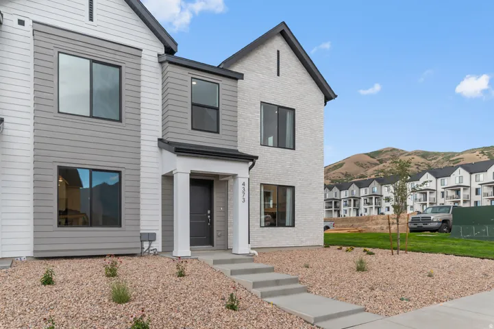 Contemporary exterior with a covered entry, stone and siding facade, and a modern black entry door