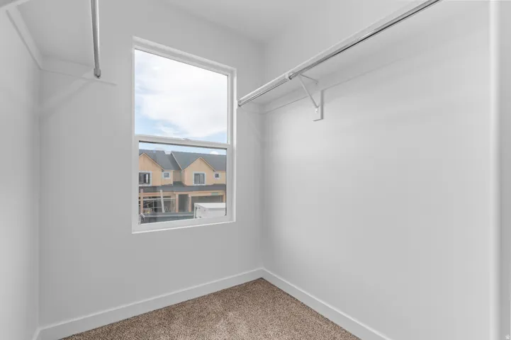 Windowed interior storage space featuring white walls and carpet flooring