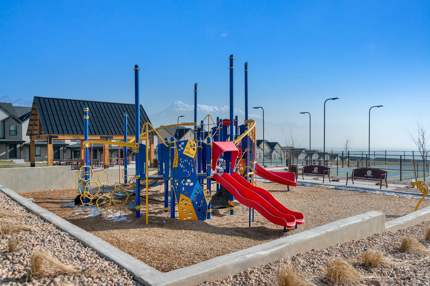 Community playground with multiple slides and climbing structures, covered picnic area, and dedicated seating