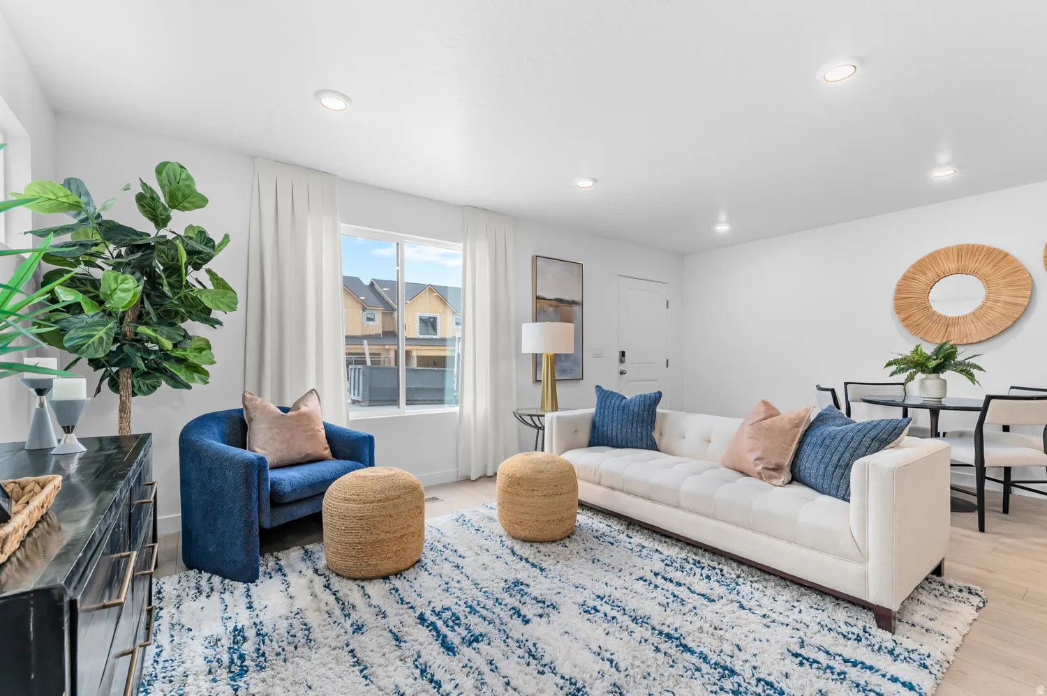Recessed lighting, light wood-finish flooring, white walls, and a large window with white blinds