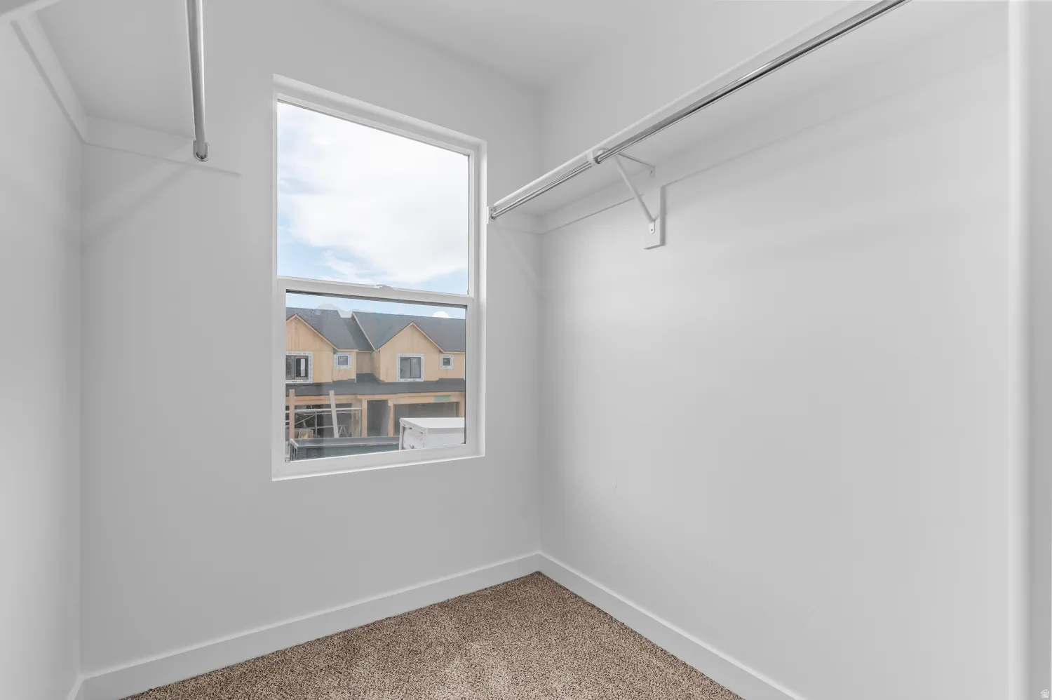 Windowed interior storage space featuring white walls and carpet flooring