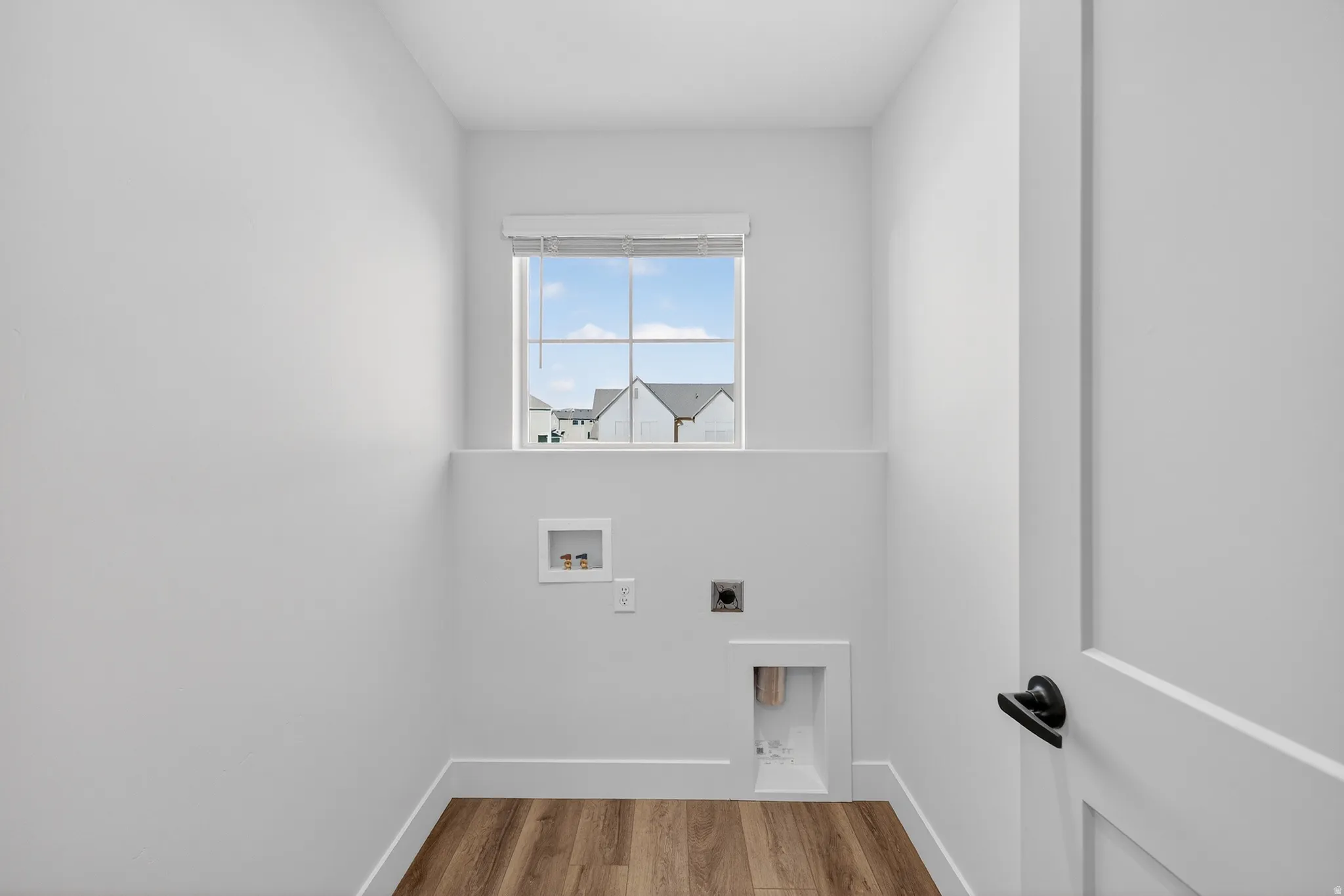 Compact utility space featuring wood-finish flooring, a single window, and white walls
