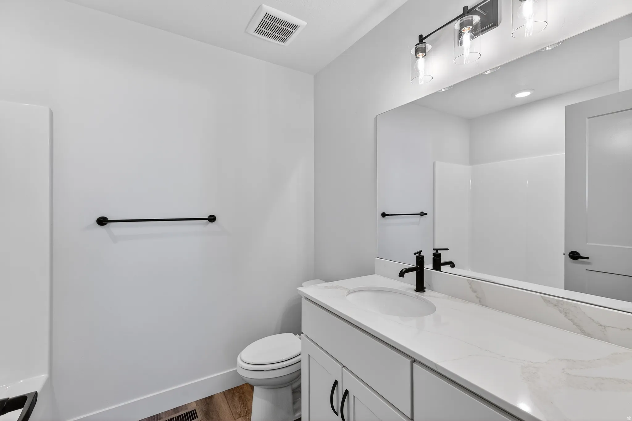 White vanity with a single basin, stone-finish countertop, and matte black faucet