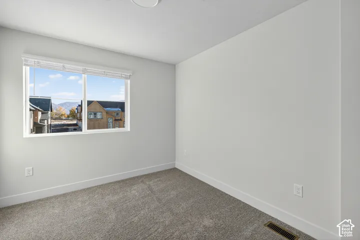 Light gray carpeting and white painted walls with a single window featuring blinds