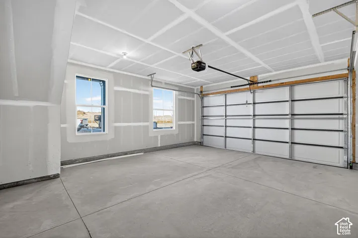 Spacious garage featuring a concrete floor, two windows, and an automated garage door system