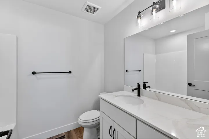 White vanity with a single basin, stone-finish countertop, and matte black faucet