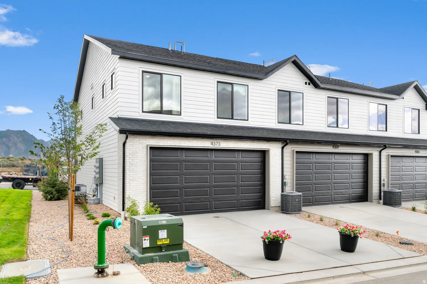 Modern exterior featuring white siding, dark trim windows, a dark shingle roof, and a single-car garage