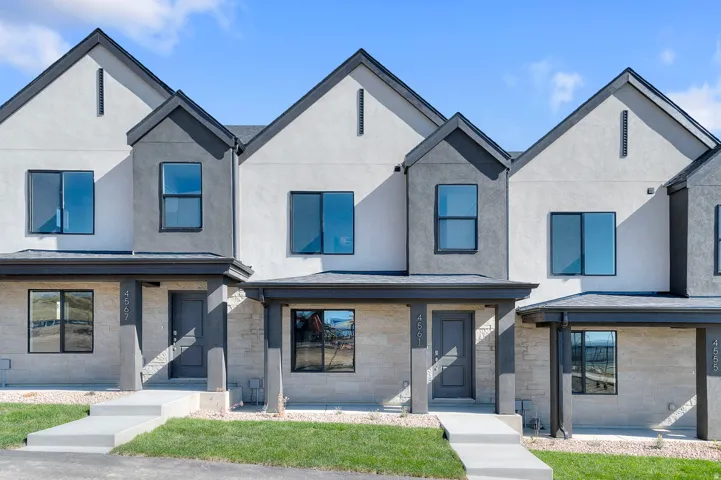 Modern townhome exterior featuring a neutral color palette, stone veneer accents, pitched roofs, and covered entryways
