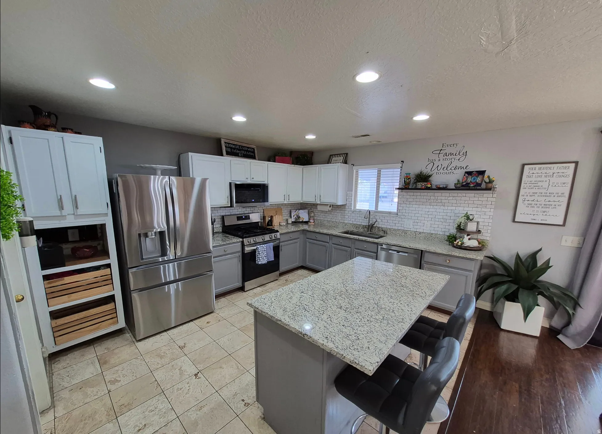 Kitchen featuring stainless steel appliances, granite countertops, white upper cabinetry, gray lower cabinetry, and a tile backsplash