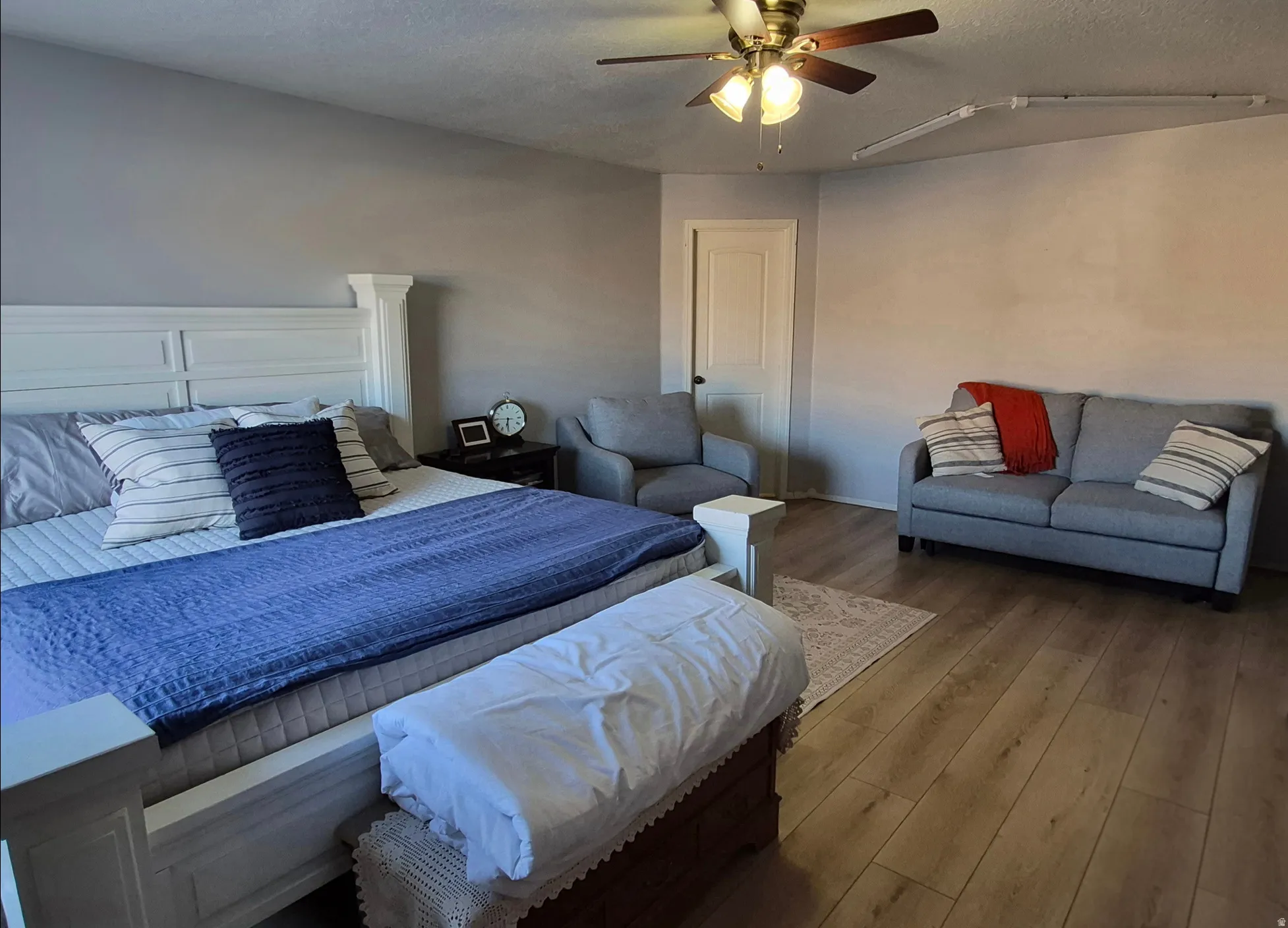 Vaulted ceiling with a ceiling fan, wood-finish flooring, and light gray wall paint