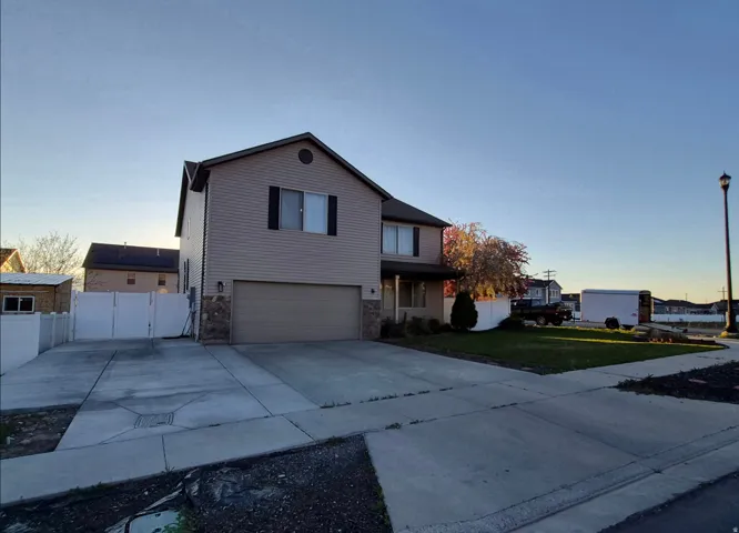 Two-story residence featuring siding and stone facade, an attached garage, and a concrete driveway