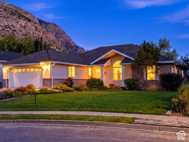Single-story residential architecture with an attached two-car garage, manicured lawn, and established landscaping