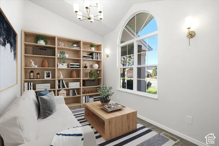 Light-filled home office featuring custom wood-finish built-in shelving with display and storage capacity, arched transom window with multiple panes, wood-finish accent table, striped area rug, and brass wall sconce lighting