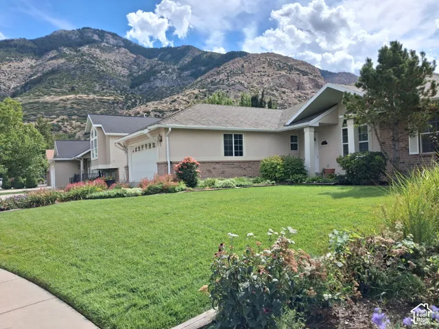 Expansive front lawn with established landscaping, a paved walkway, and a home exterior featuring stucco and brick accents