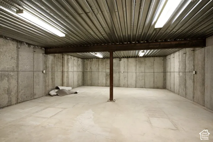 Concrete foundation walls with exposed beam ceiling and fluorescent lighting
