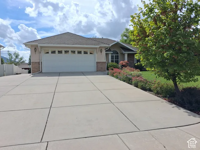 Concrete driveway, attached two-car garage with decorative windows, stucco and brick exterior, established landscaping, RV parking
