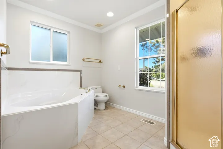 Tiled flooring with a built-in soaking tub, a separate shower enclosure, and a frosted window