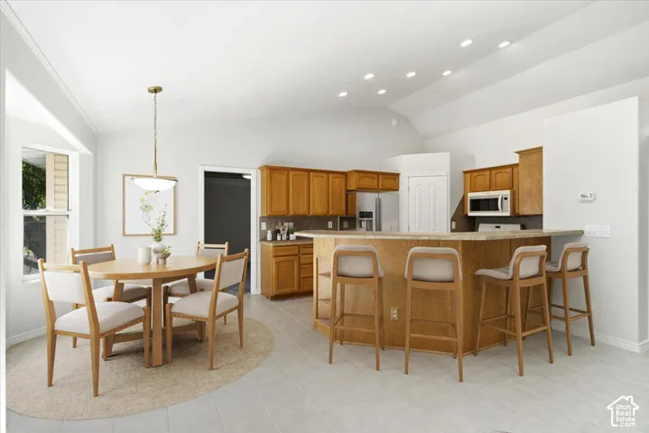 Open-concept kitchen and dining area featuring a vaulted ceiling with recessed lighting
