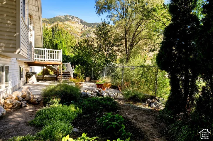 Siding exterior with an elevated deck featuring white railings, leading to a ground-level patio area