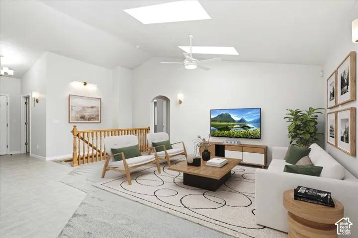 Bright, open-concept living area with vaulted ceilings, skylight, and ceiling fan