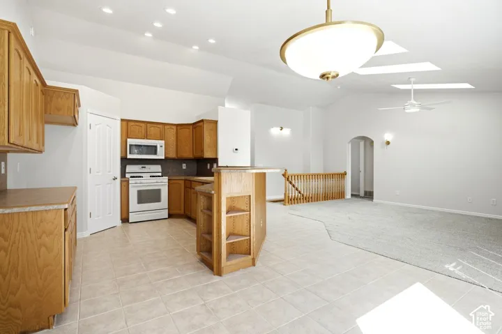 Kitchen featuring wood cabinetry, white appliances, and tile flooring