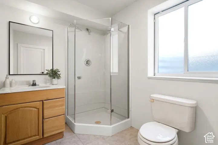 Wood-finish vanity with an integrated sink, rectangular mirror, and an enclosed glass shower