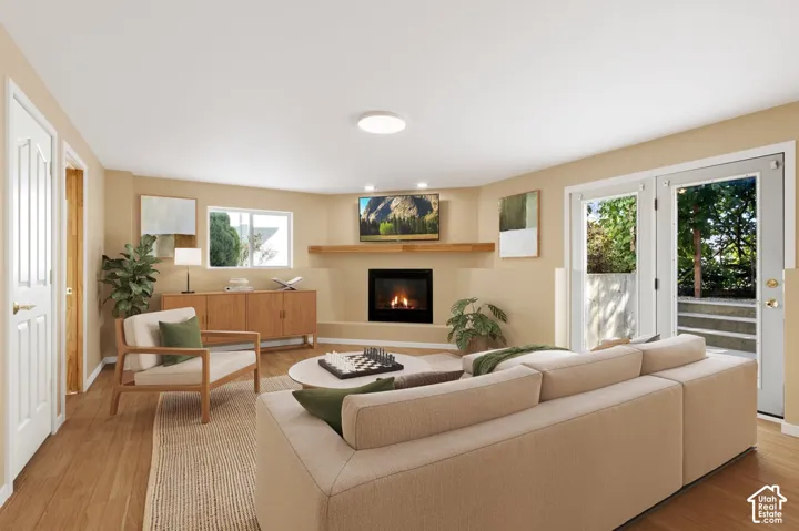 Living space featuring wood-finish flooring, a fireplace with a wood mantel, a window, and double doors to the exterior