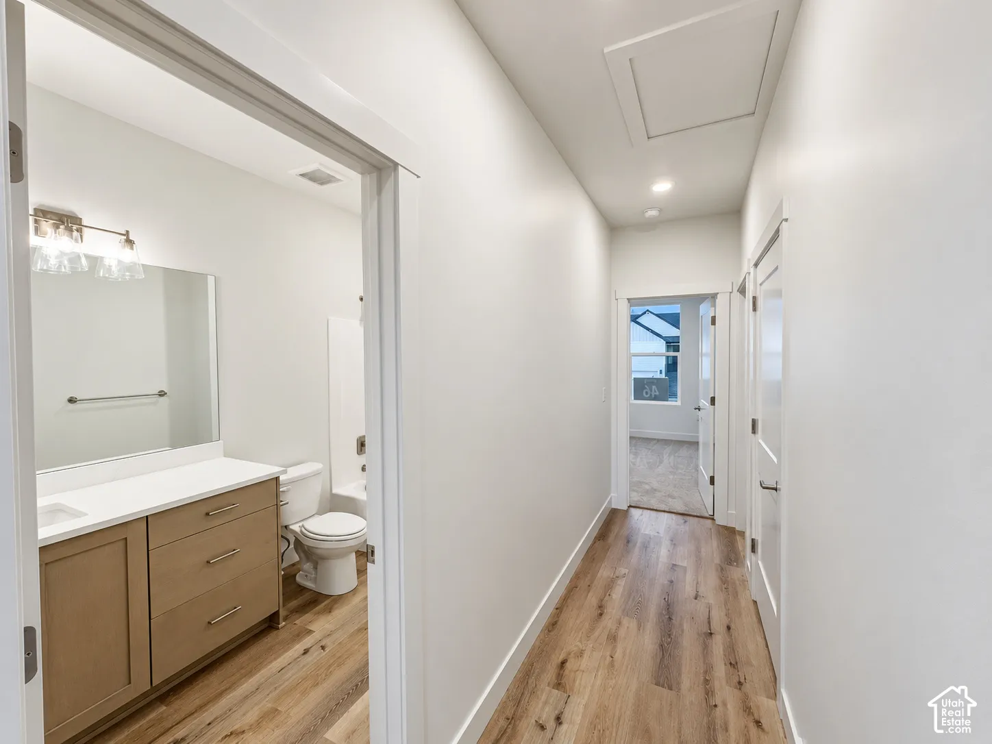 Hallway featuring wood-finish flooring, recessed lighting, and a white interior door