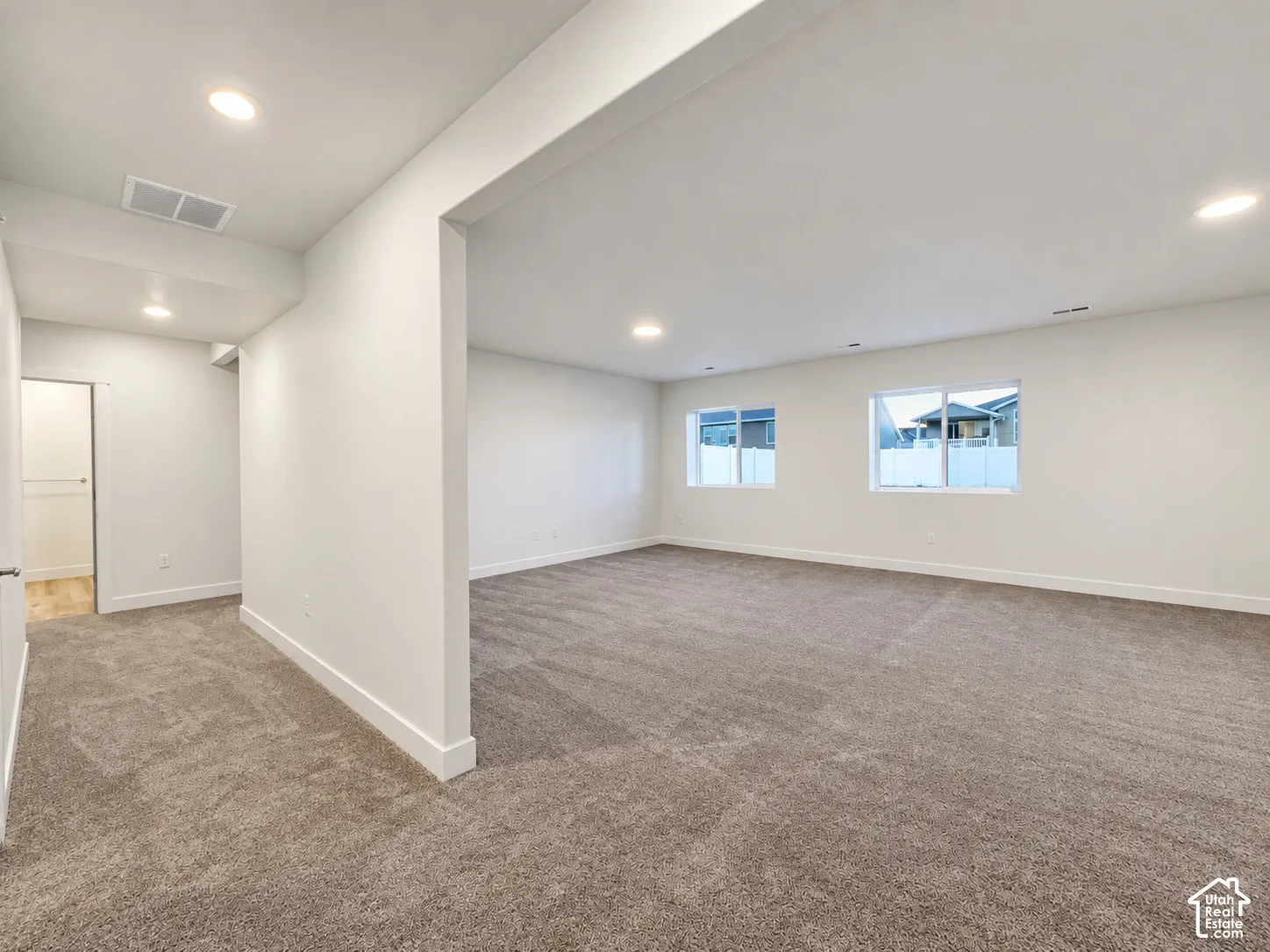 Expansive room featuring recessed lighting, light-toned carpeting, white walls, and multiple windows