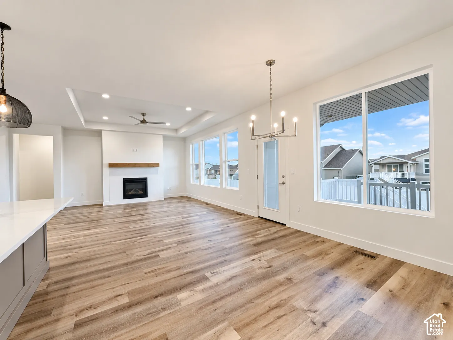 Spacious interior featuring wood-finish flooring, a contemporary fireplace with a wood mantle, a tray ceiling with recessed lighting, and multiple windows