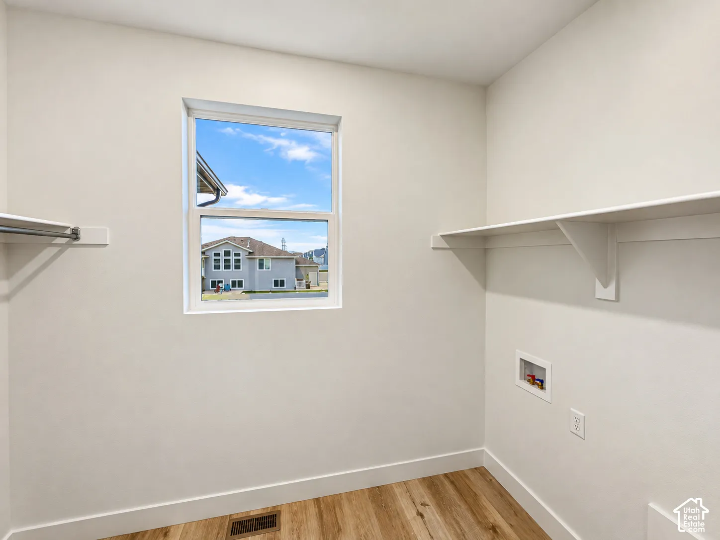 Wood-finish flooring, built-in shelving, a single window, and a built-in hanging rod